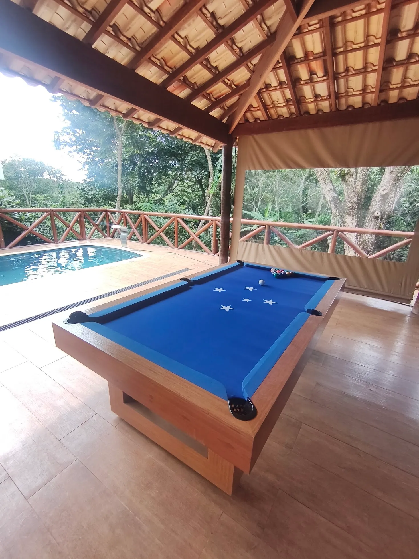 Mesa de bilhar em madeira natural instalada em área de lazer