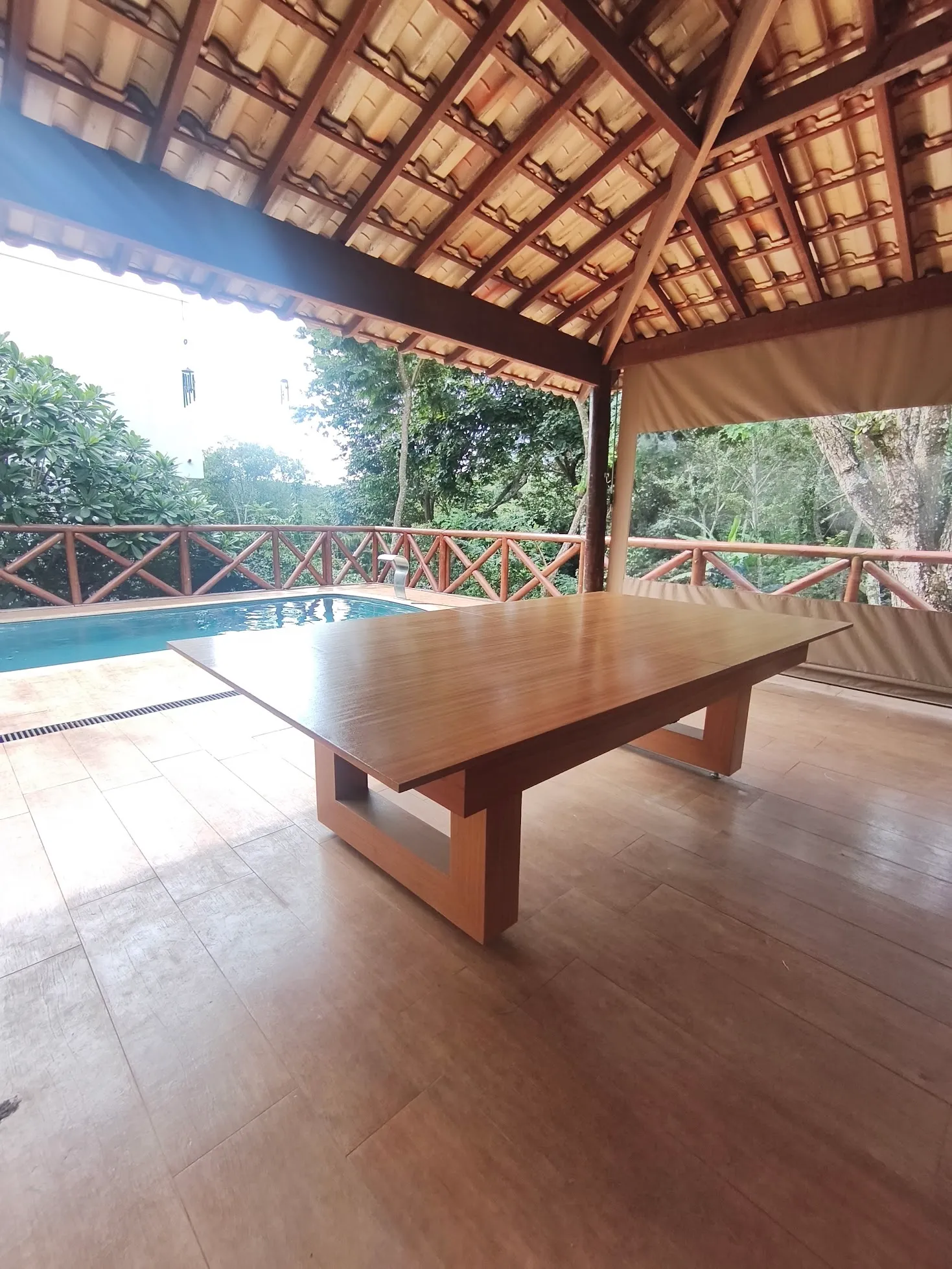 Mesa de jantar em madeira natural instalada ao lado de uma piscina