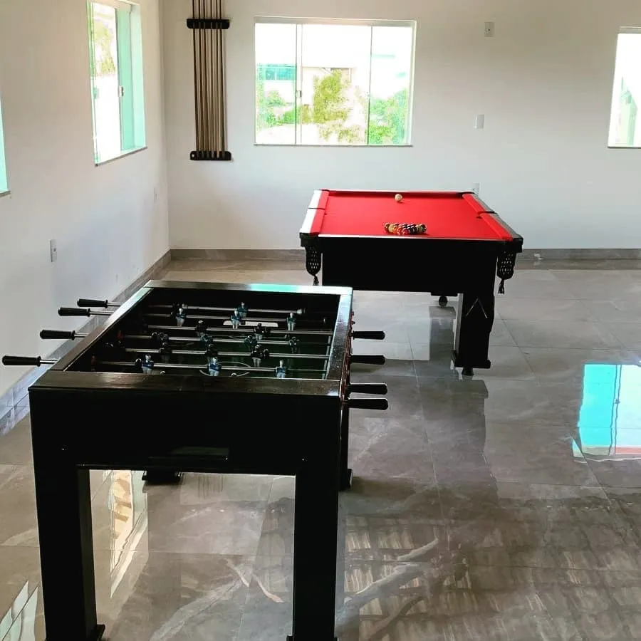 Mesa de totó preta em ambiente ao lado de uma mesa de sinuca vermelha