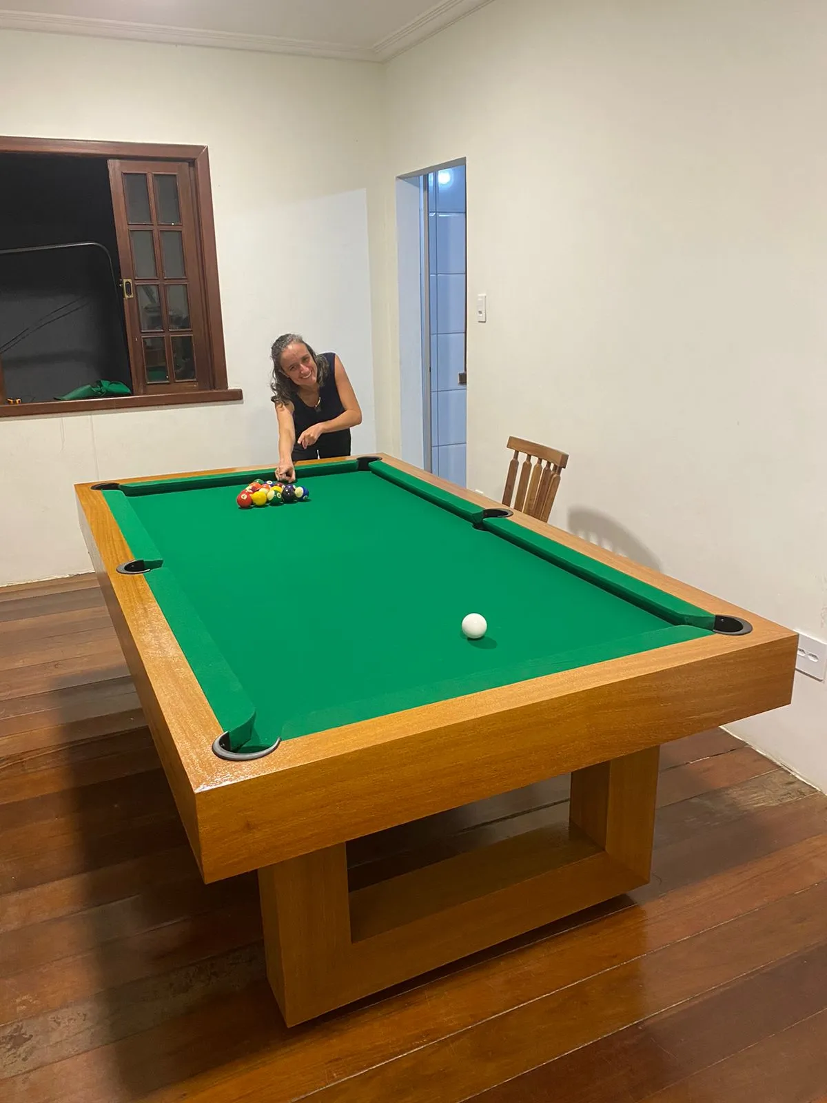 Mesa de bilhar de madeira com tecido verde em ambiente interno